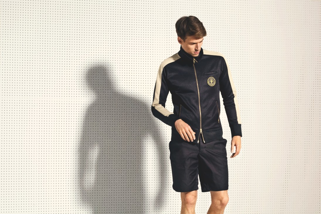 Male model wearing Tools nylon jersey tracksuit with navy and cream colorblock design and detachable badge.
