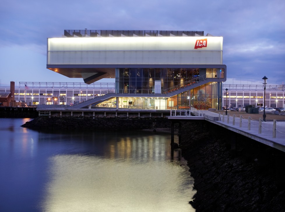 Institute of Contemporary Art building with illuminated white corrugated metal facade and ICA logo overlooking Fort Point Channel at dusk.
