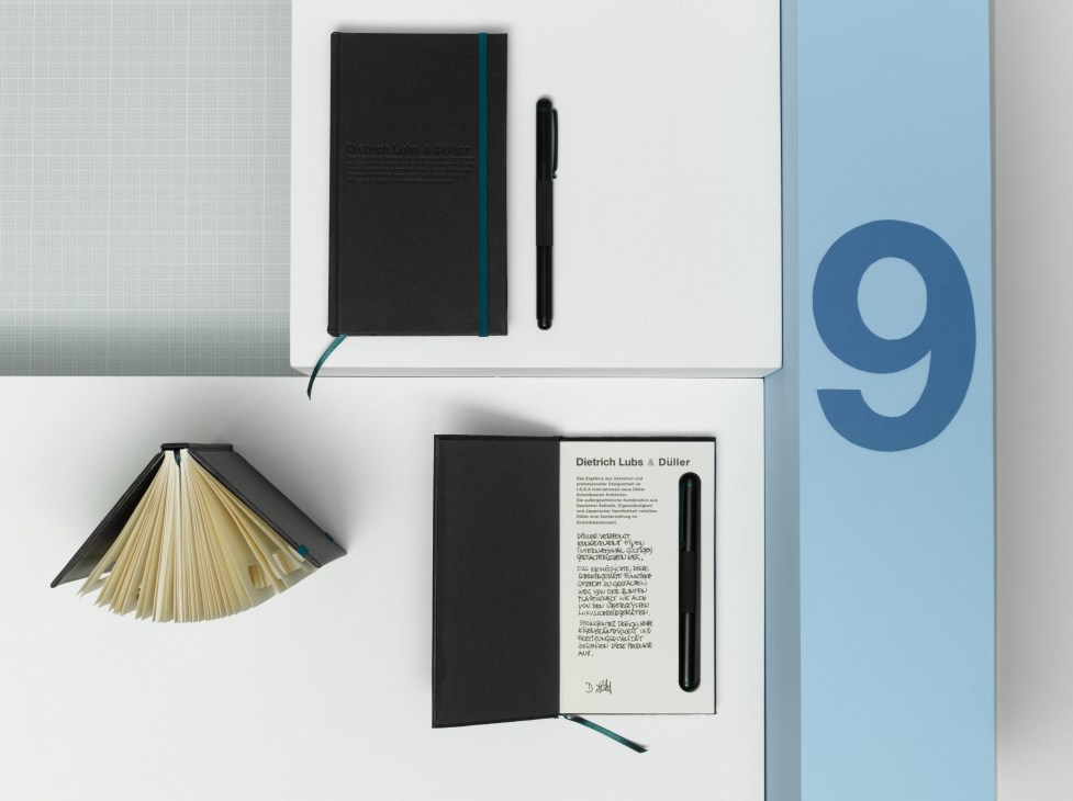 Düller stationery collection featuring black aluminium pens and matching notebooks with teal accents.
