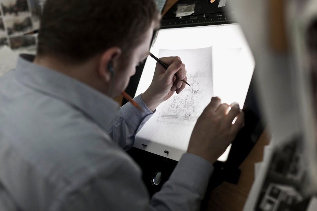 Animator sketching designs on a light table at Brown Bag Films studio.