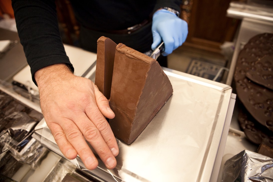 Hands holding a large triangular bar of gianduja chocolate at Guido Gobino chocolatier.