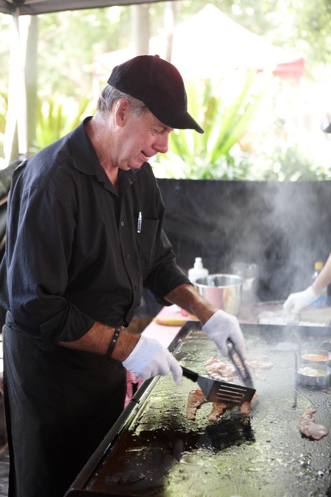 Peter Moss cooking egg and bacon rolls at Bowen's stall at Kings Cross market in Sydney.