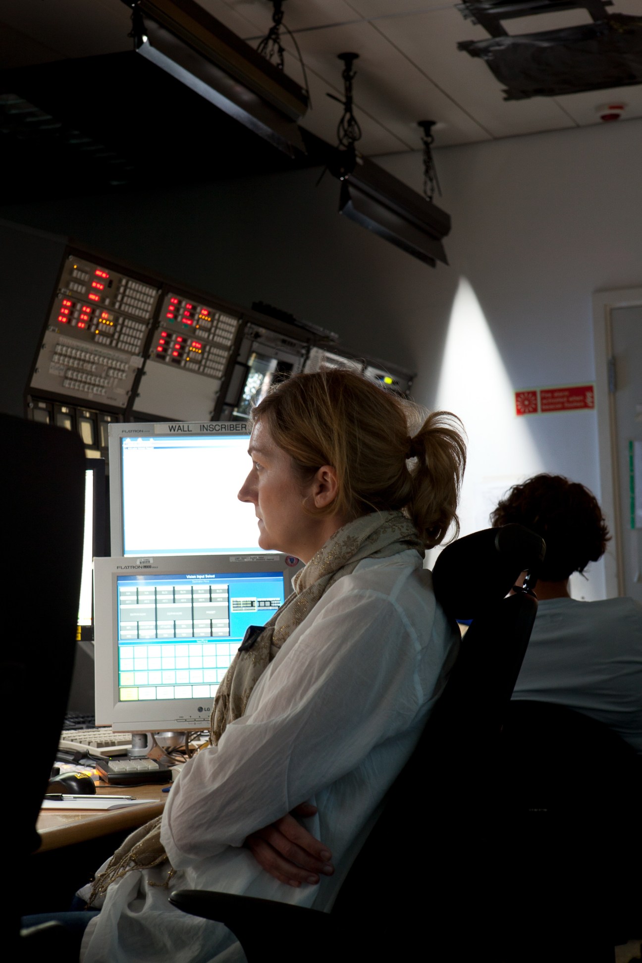 Producer at Channel 4 News control room monitoring broadcasts on computer screens.
