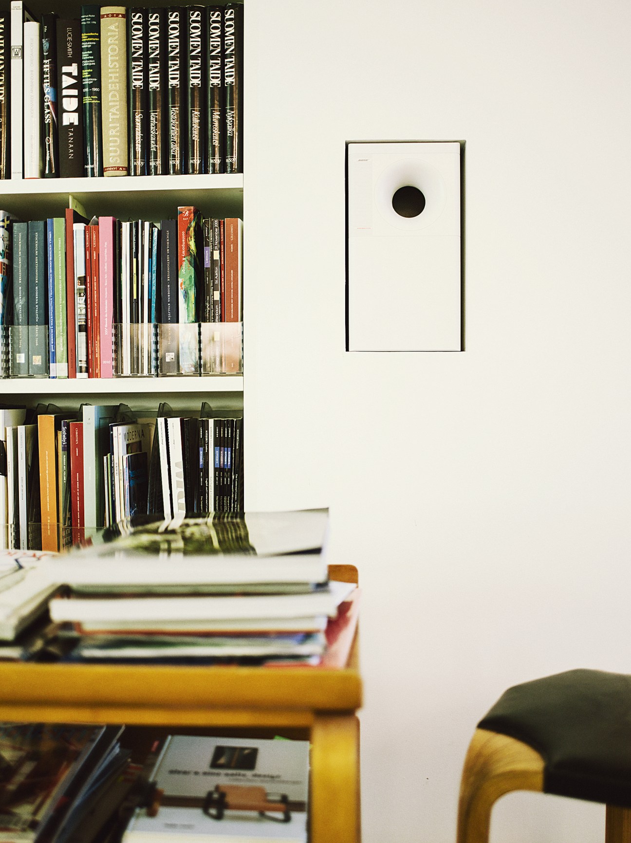 Built-in bookshelves with recessed lighting and a handleless cupboard door on a white wall.