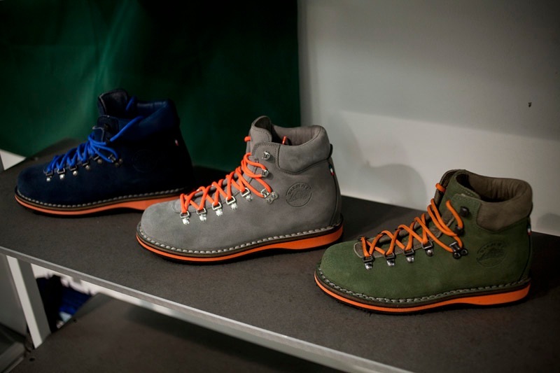 Three Diemme hiking boots displayed on a shelf with orange laces and contrasting color uppers.