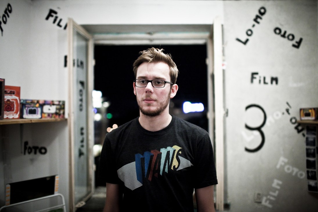 Young man wearing glasses and black t-shirt stands in Lomo photo shop at 5.10.15 in Warsaw.
