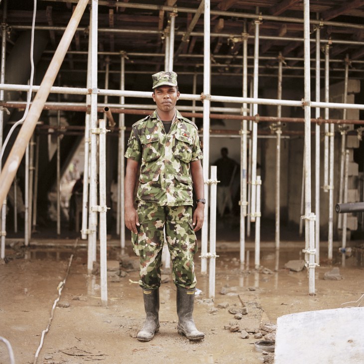 Sri Lankan army soldier in camouflage uniform standing within steel scaffolding at a construction site.