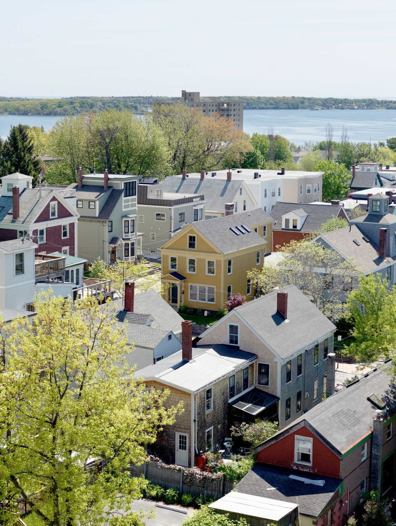 Aerial view of Munjoy Hill's colorful residential houses with water and distant shoreline in background