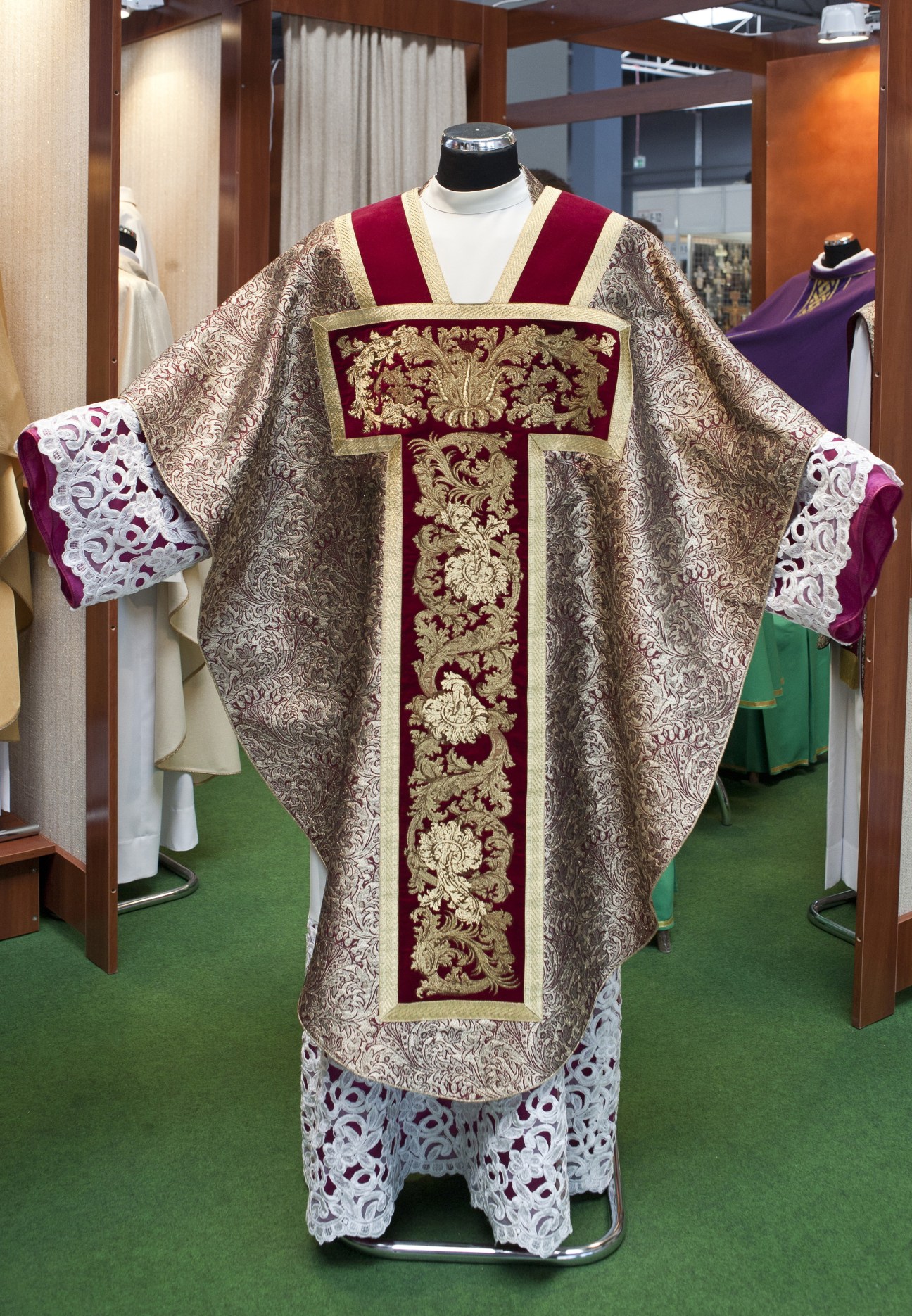 Ornate gold and burgundy ecclesiastical vestment displayed on mannequin at SacroExpo trade fair.