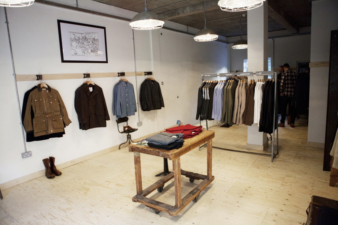 Interior of Private White flagship store showing clothing displays on walls and racks with wooden table.