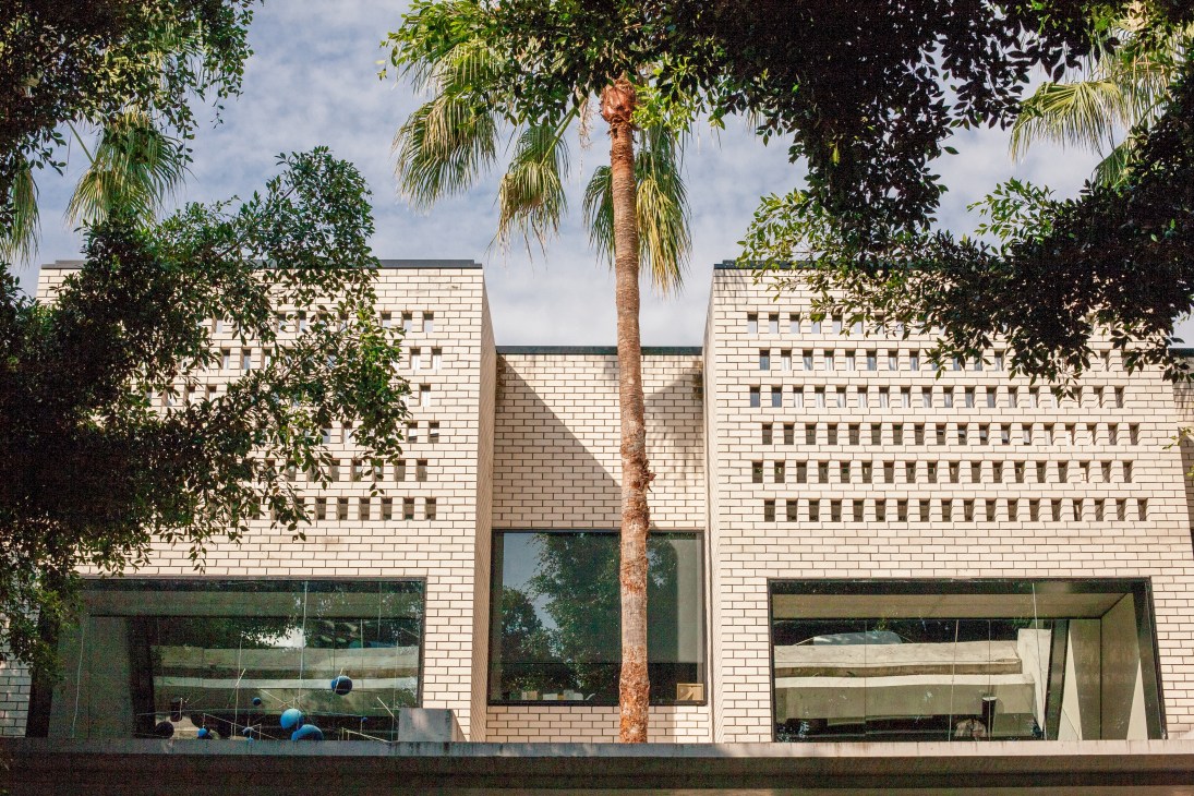 Modern brick building with large windows and palm tree in foreground.