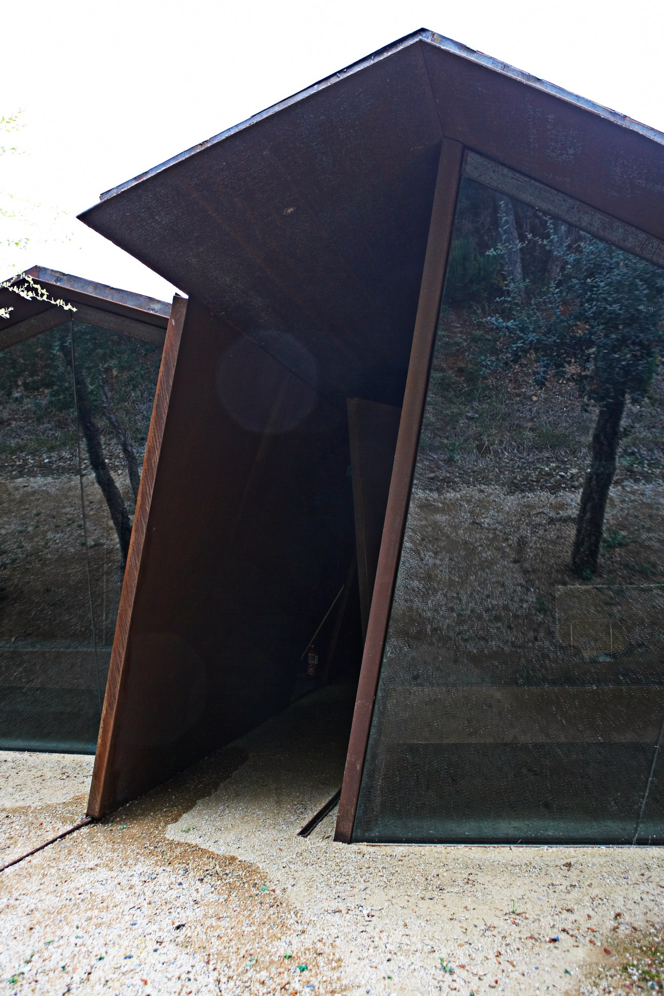 Dark wooden angular structure with glass panels showing forest views at Rough Luxe Experience in Palamós.