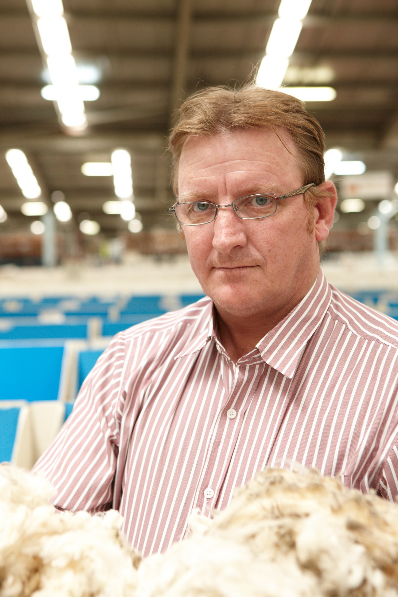 Scott Carmody, wool buyer for Lempriere, poses at a wool selling centre with fleece samples.