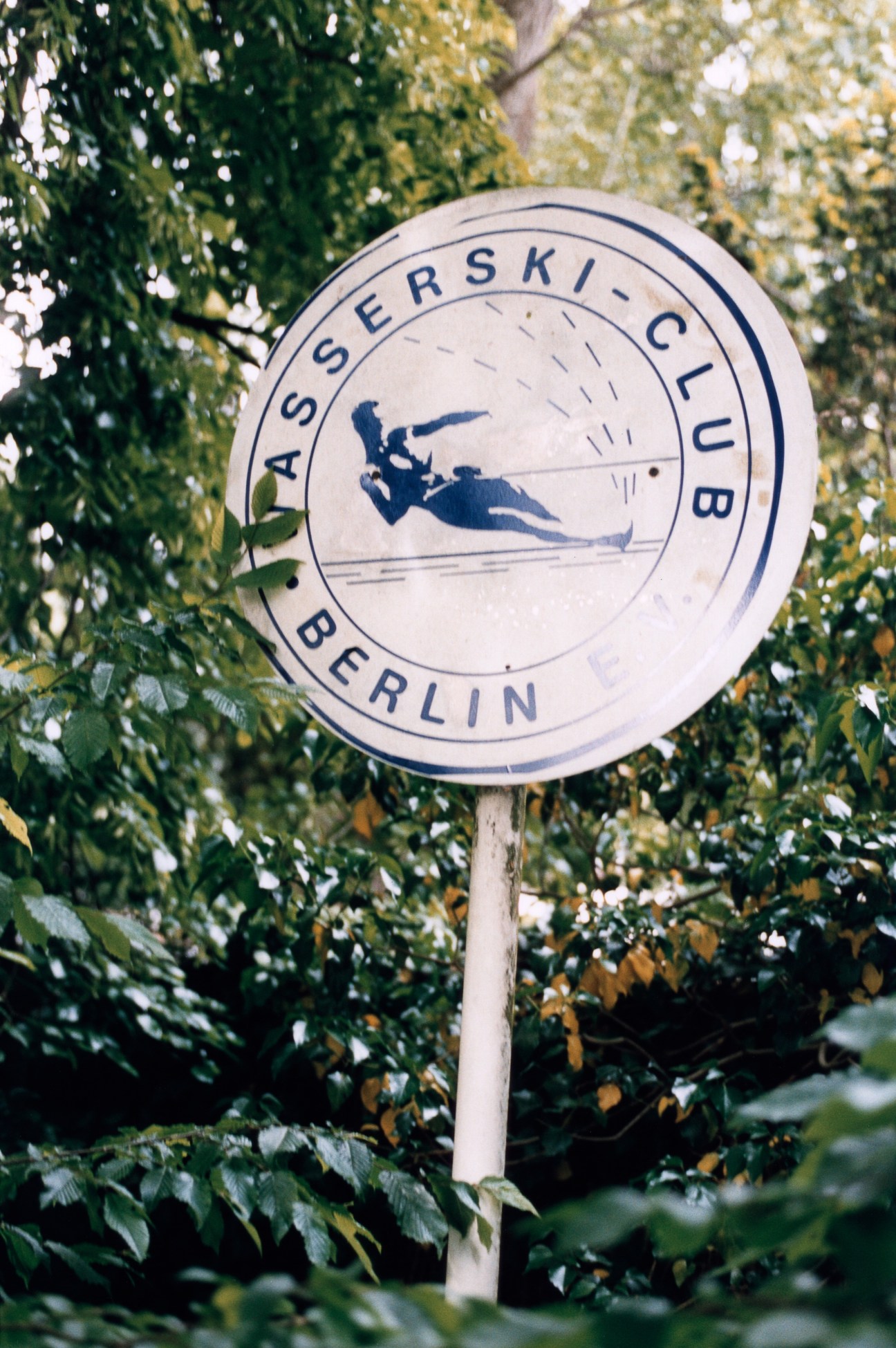 Circular sign for Asserski-Club Berlin waterski club among green foliage