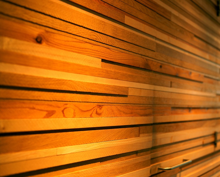 Close-up of wooden screen with horizontal slats in warm wood tones and metal accents.