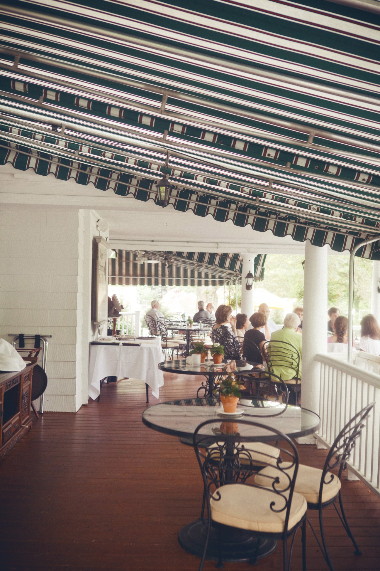 Shaded porch at Roger Sherman Inn with diners seated at tables under striped awning.