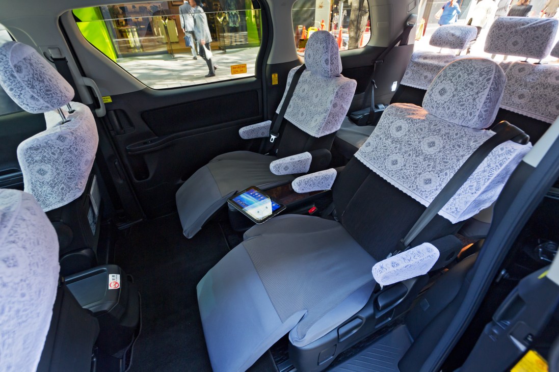 Interior of a Toyota Alphard minivan showing spacious seating with patterned seat covers and leather upholstery.