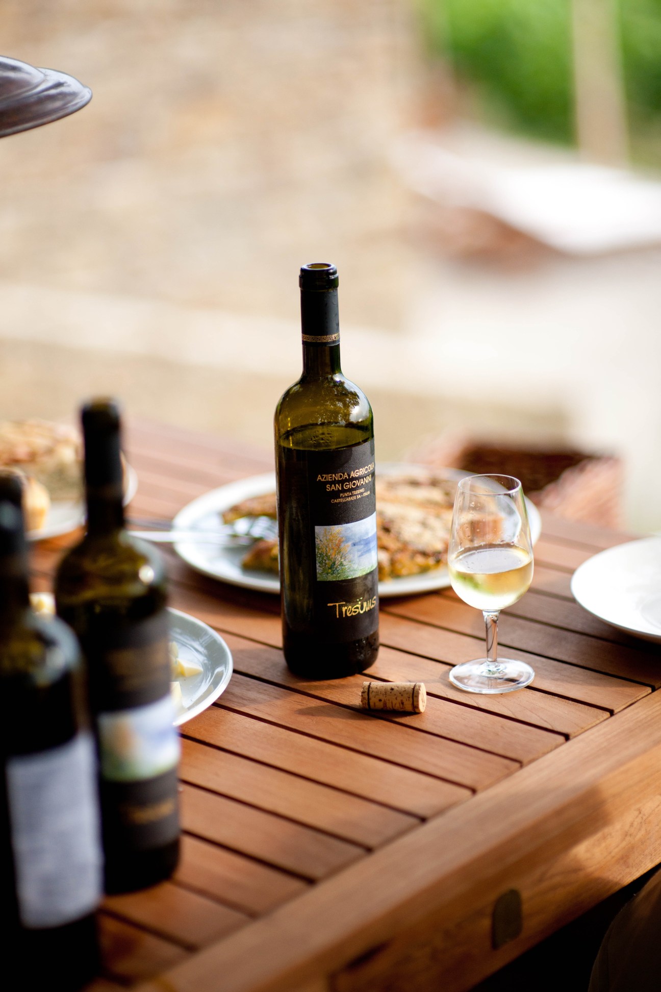 Wine bottle and glass on wooden table at Punta Tresino holiday cottage in Italy.