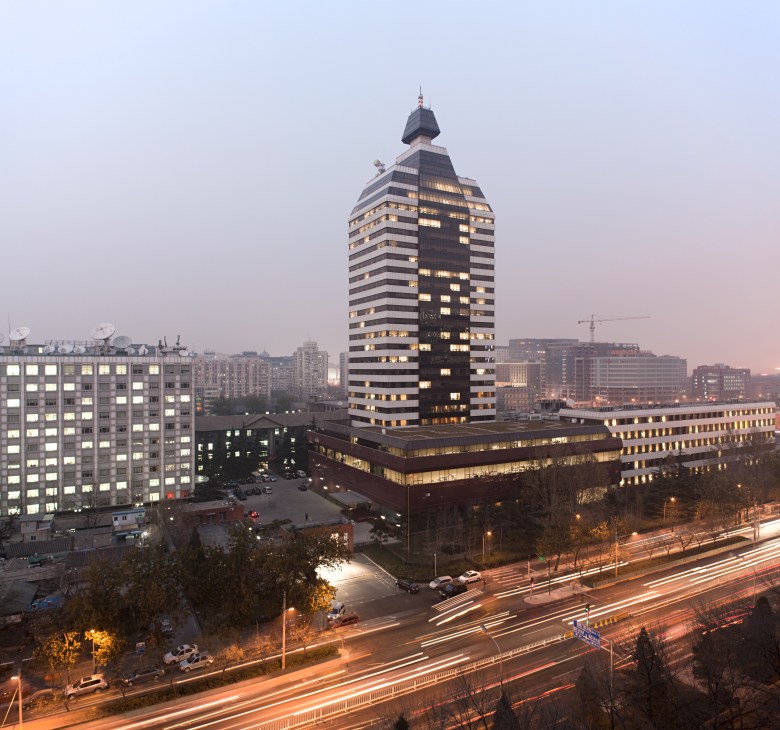 Xinhua Tower illuminated at dusk in Beijing's Xuanwu District surrounded by other buildings.