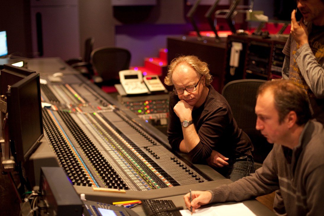 FFS employees work at a mixing desk with illuminated controls in a Munich dubbing studio.