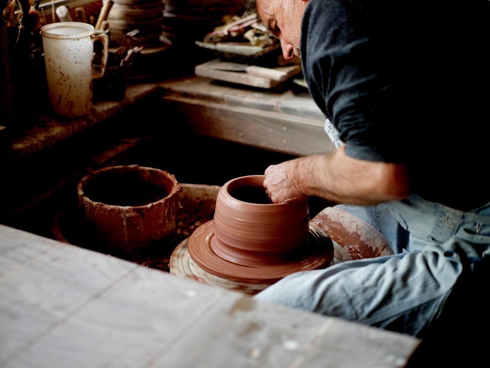 Ben Richardson shaping clay on a pottery wheel in his workshop