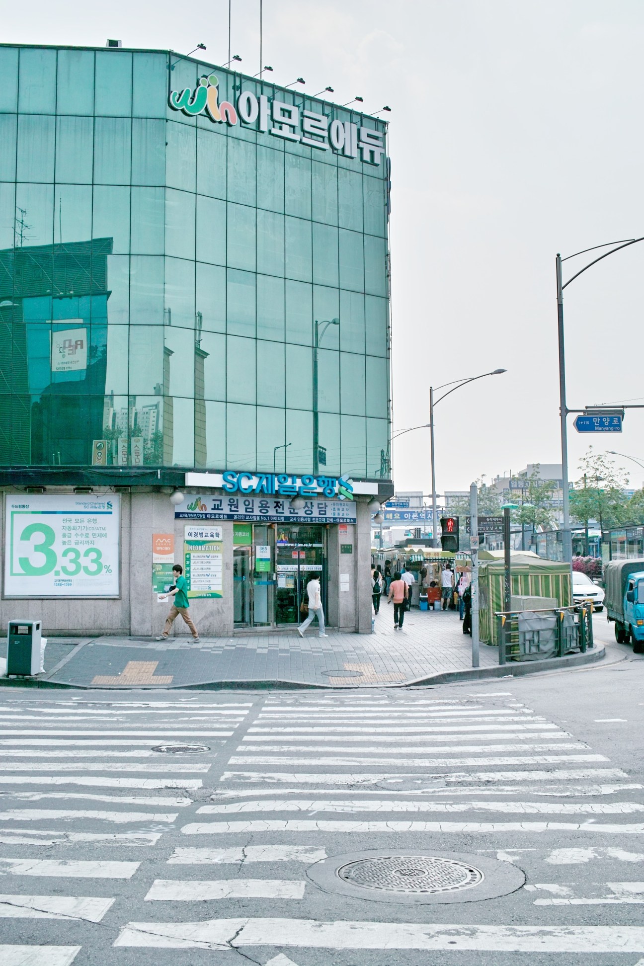 A multi-story hagwon building with Korean signage in the Noryangjin district of Seoul, with pedestrians and street-level storefronts visible.