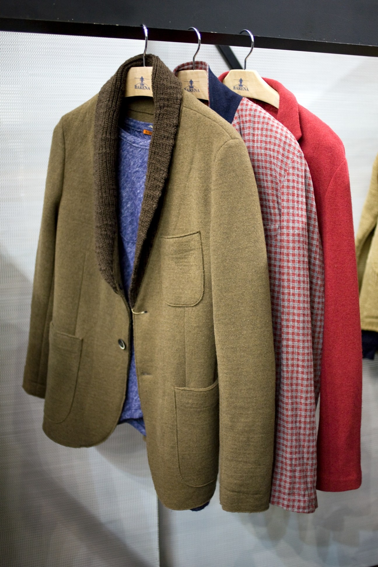 Three Barena jackets on wooden hangers displaying relaxed tailoring in neutral and patterned fabrics.