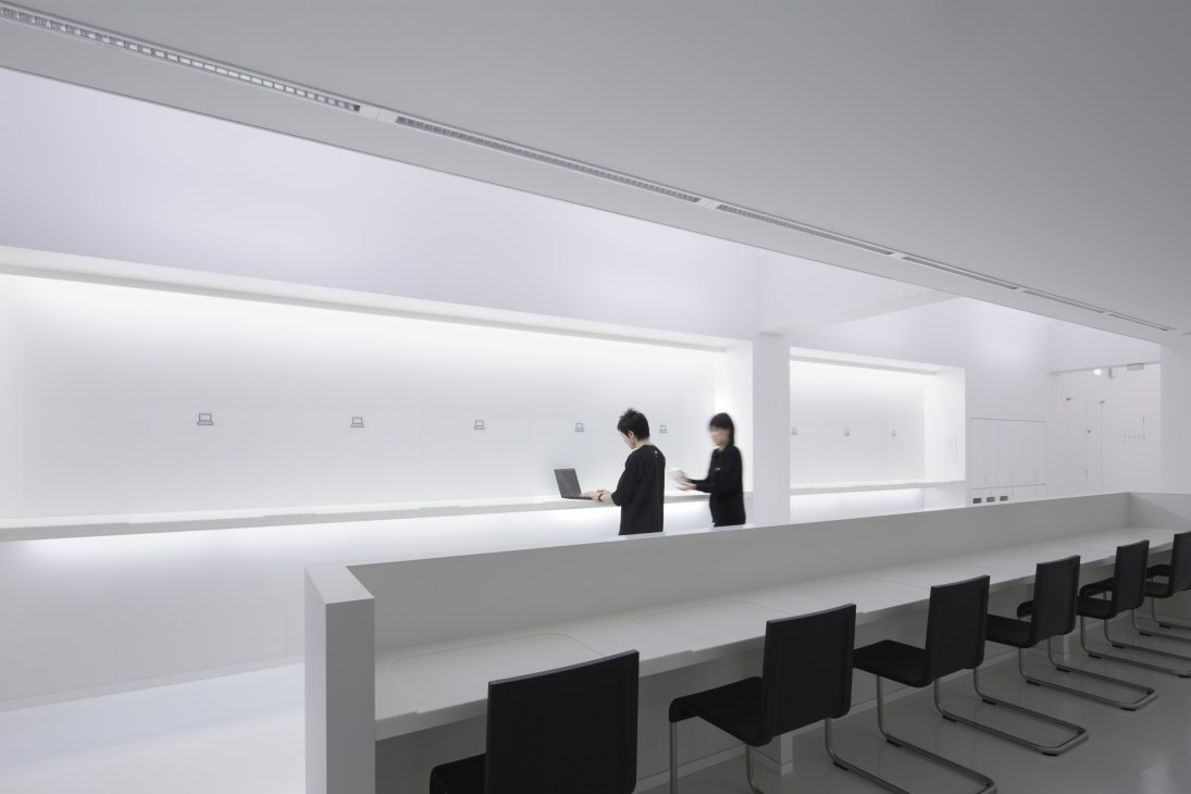 Modern minimalist hotel lobby with white counter, staff in black uniforms, and integrated lighting in 9 hours Kyoto.