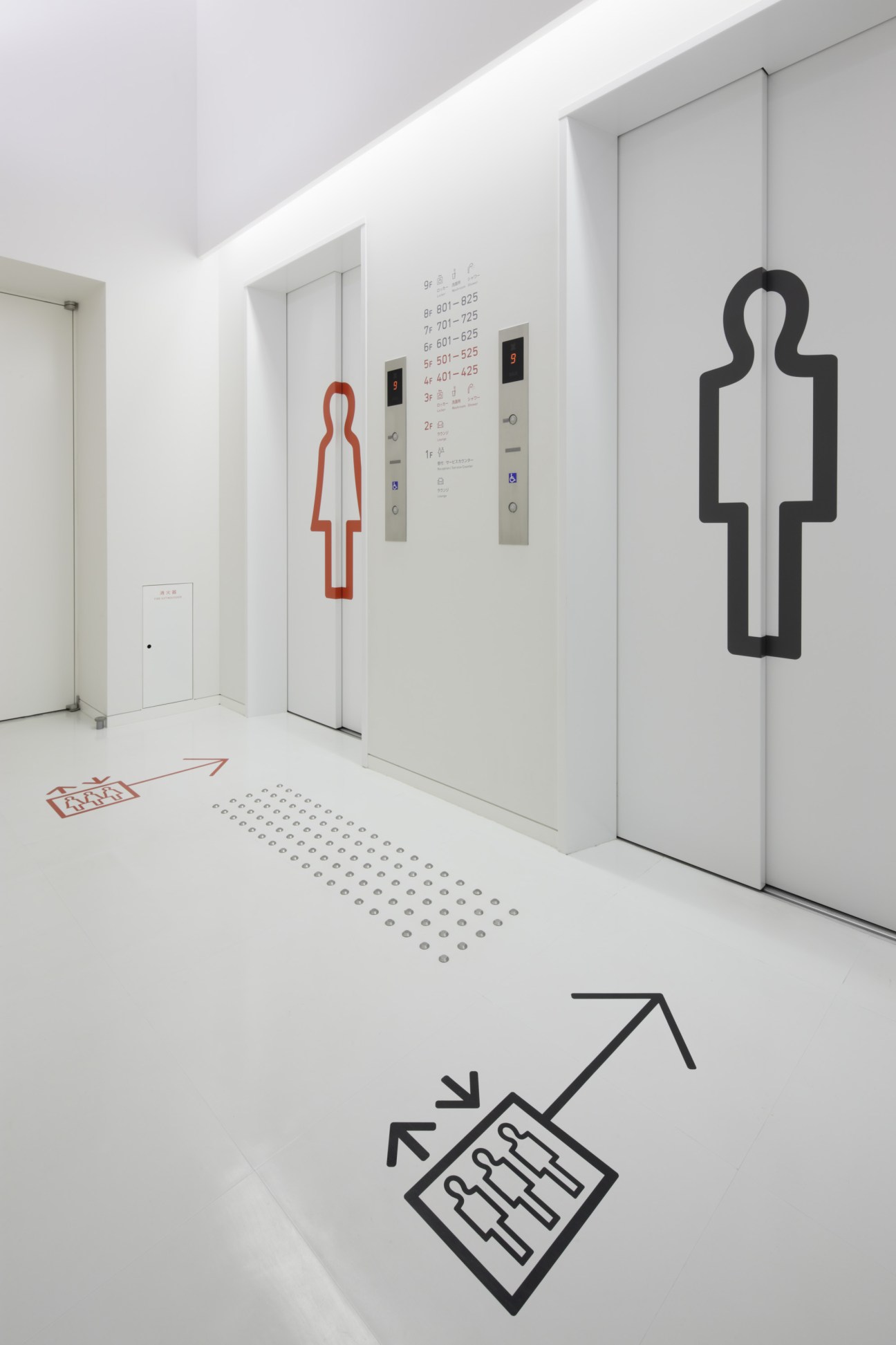 Elevator hallway with bold graphic signage showing male and female figures in red and black outlines.