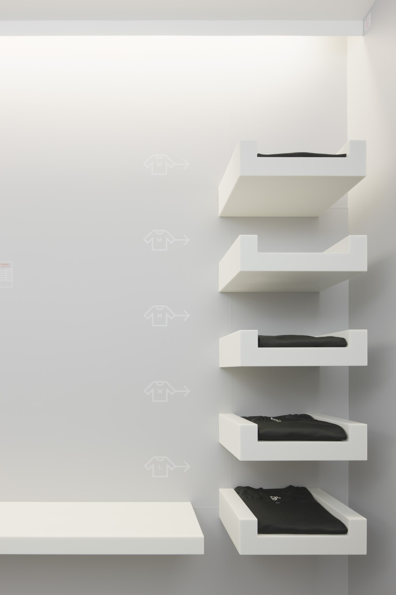 Wall-mounted white shelving displaying folded black sleepwear and amenities at 9 hours hotel Kyoto.