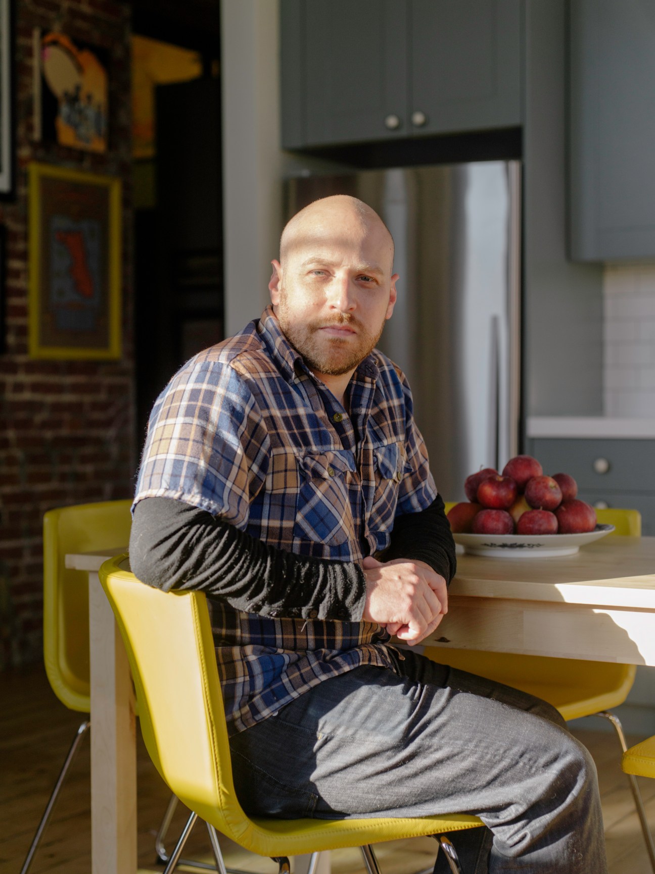 Brian Mendelssohn sits on a yellow chair in his kitchen in Lawrenceville.