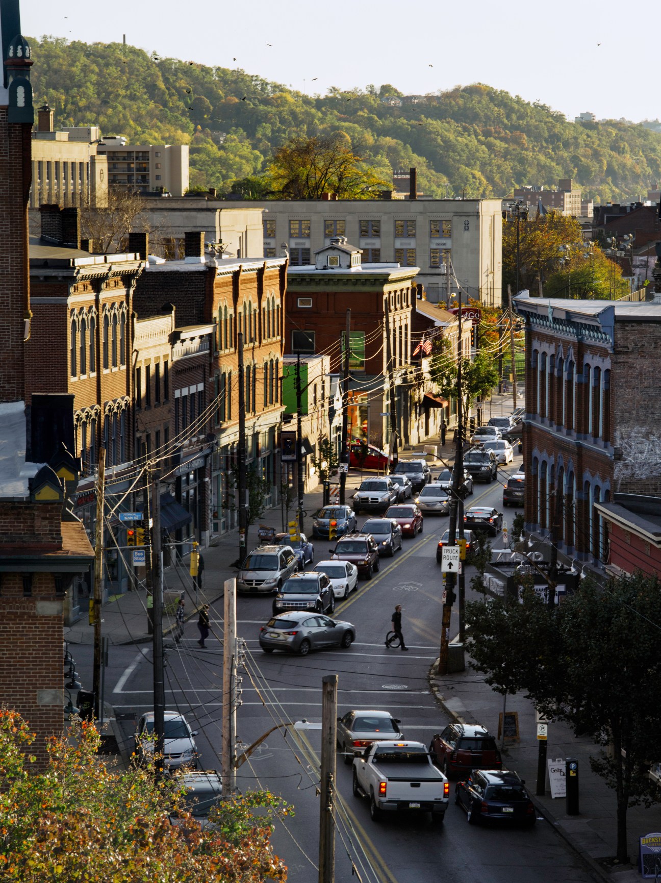 Elevated view of Butler Street in Lawrenceville, Pittsburgh, showing historic brick buildings and tree-covered hillside.