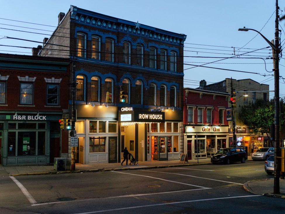 Row House Cinema storefront on a Lawrenceville street with historic brick buildings and parked cars.
