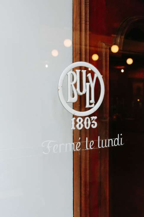 Buly 1803 circular white logo signage on wooden door frame with 'Fermé le lundi' text below.
