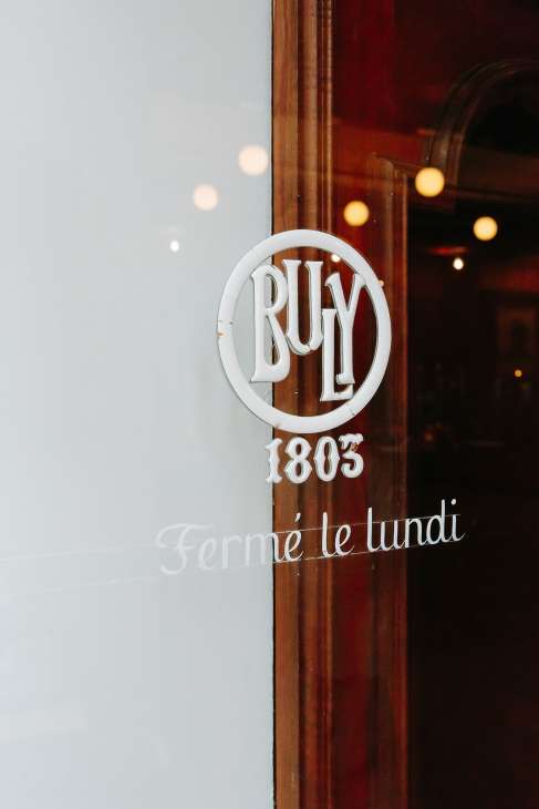Buly 1803 circular white logo signage on wooden door frame with 'Fermé le lundi' text below.