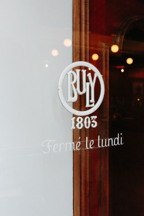 Buly 1803 circular white logo signage on wooden door frame with 'Fermé le lundi' text below.