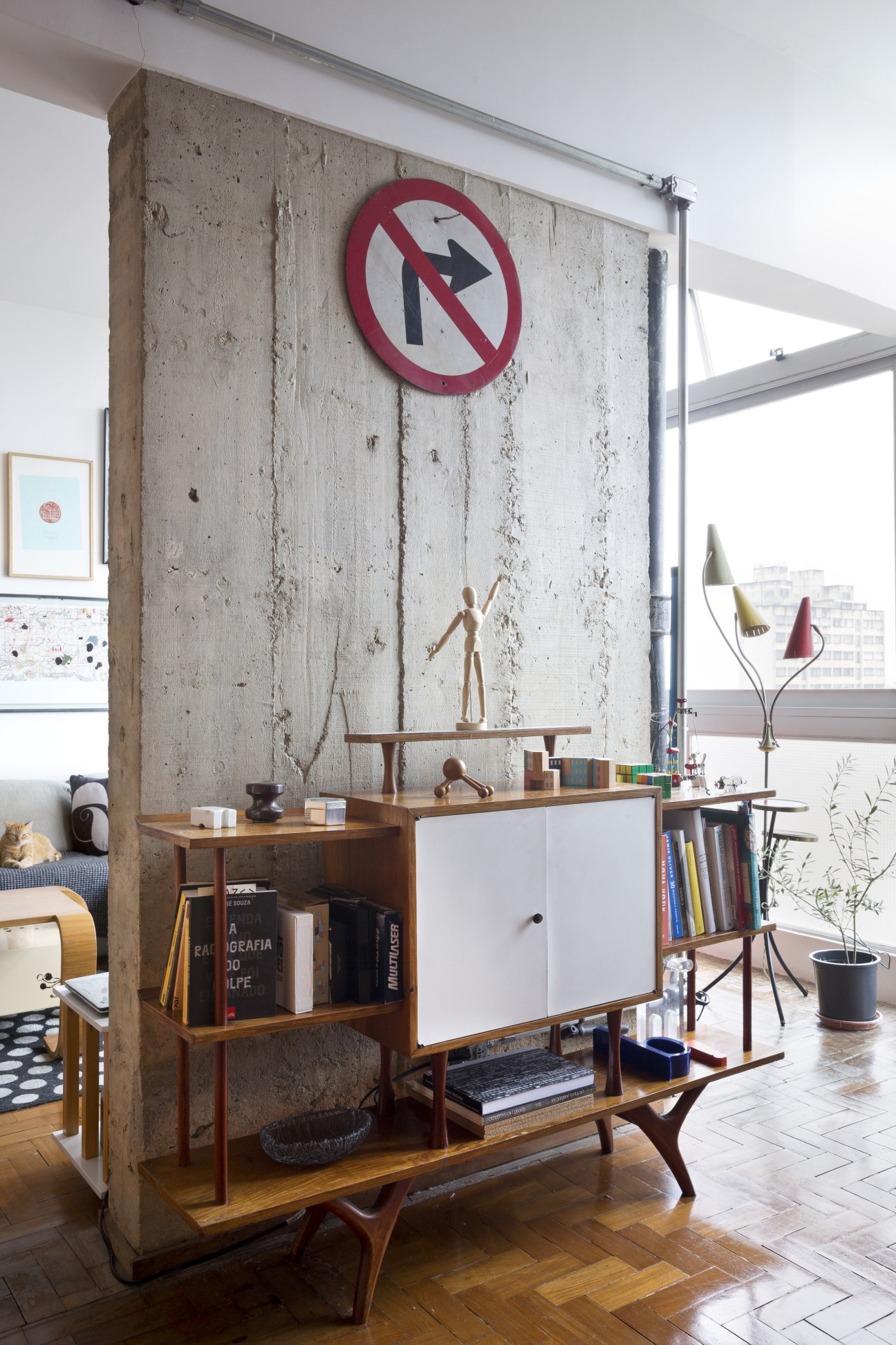 Concrete apartment interior with wooden mid-century furniture and a red no-right-turn traffic sign on the wall