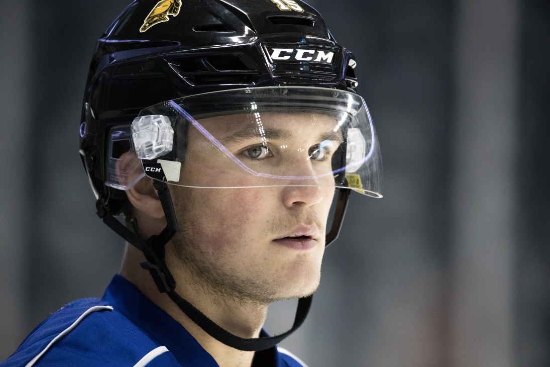 Cole Tymkin in black CCM hockey helmet with clear face shield, wearing blue jersey