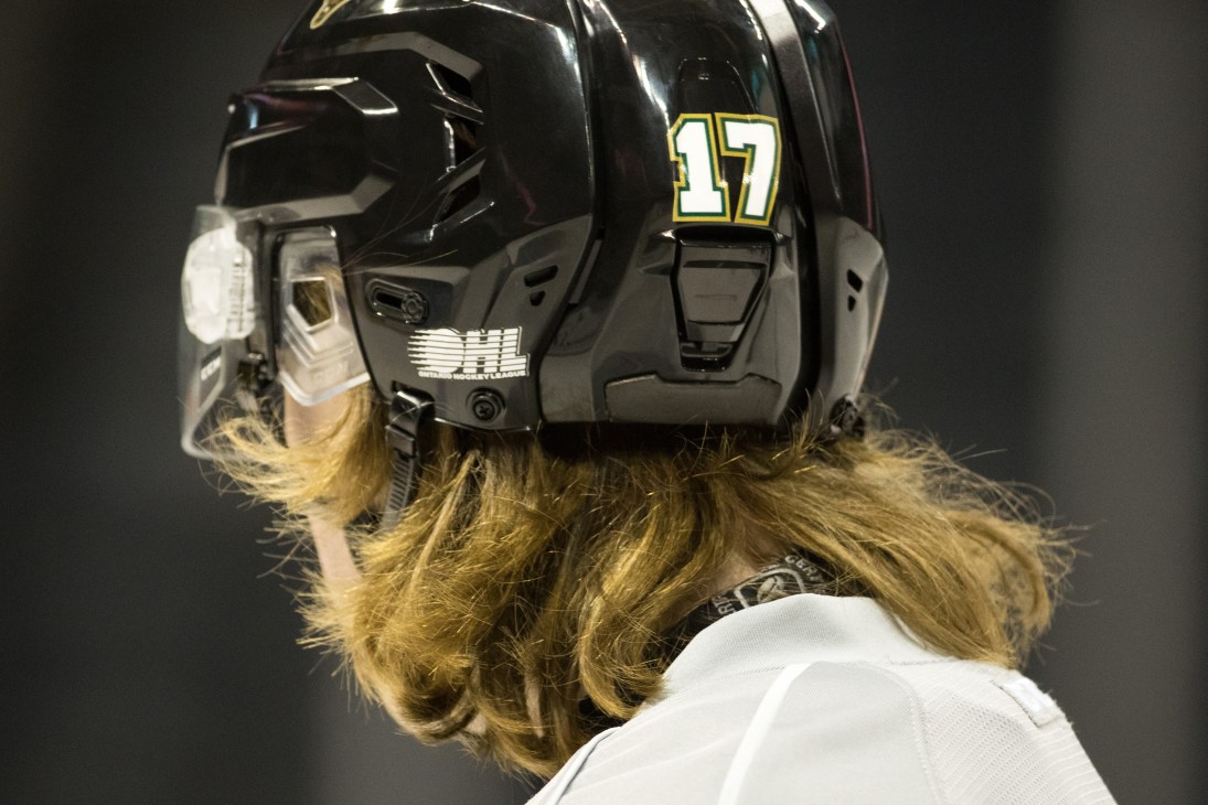 Hockey player Noah Bennett wearing black helmet with number 17, showing long blonde hair flowing from beneath