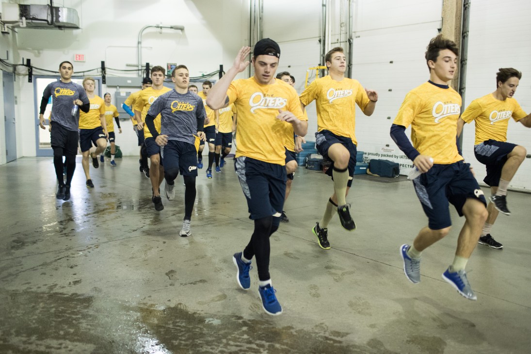 Erie Otters hockey players in yellow jerseys running during pre-game warm-up in arena