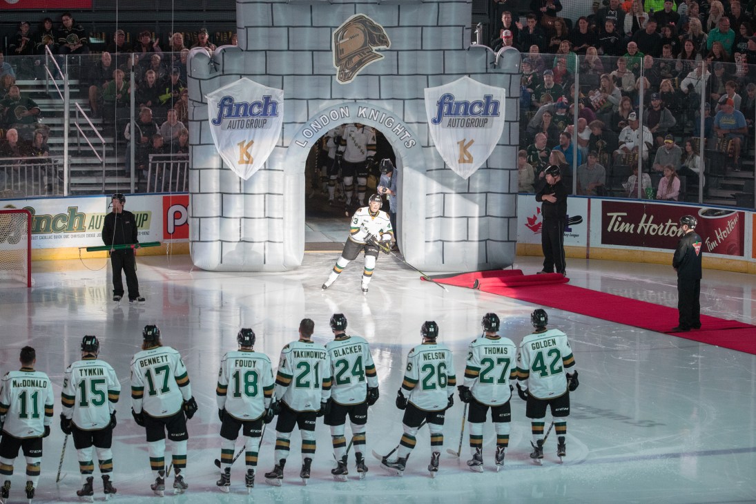 London Knights hockey players line up on ice rink in front of inflatable castle entrance with crowd in stands