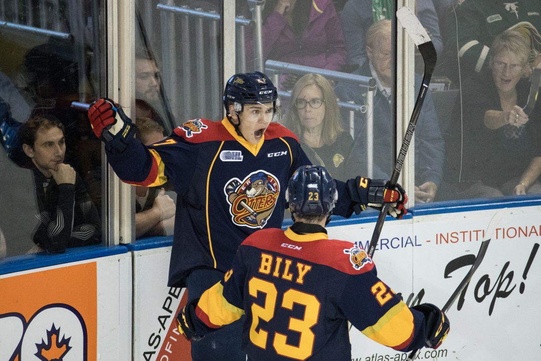 Erie Otters players celebrating a goal with raised arms while fans cheer in the background