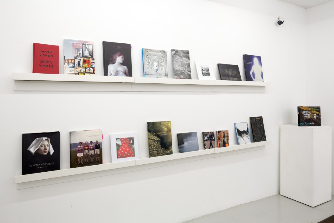 White shelves displaying art books and monographs in a gallery space
