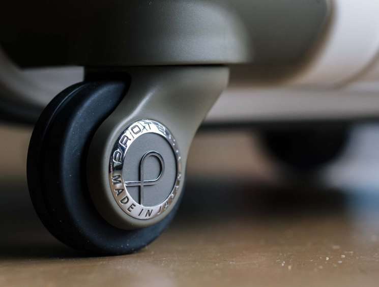 Close-up of a smooth luggage wheel on an Ace suitcase with "Made in Japan" branding visible.