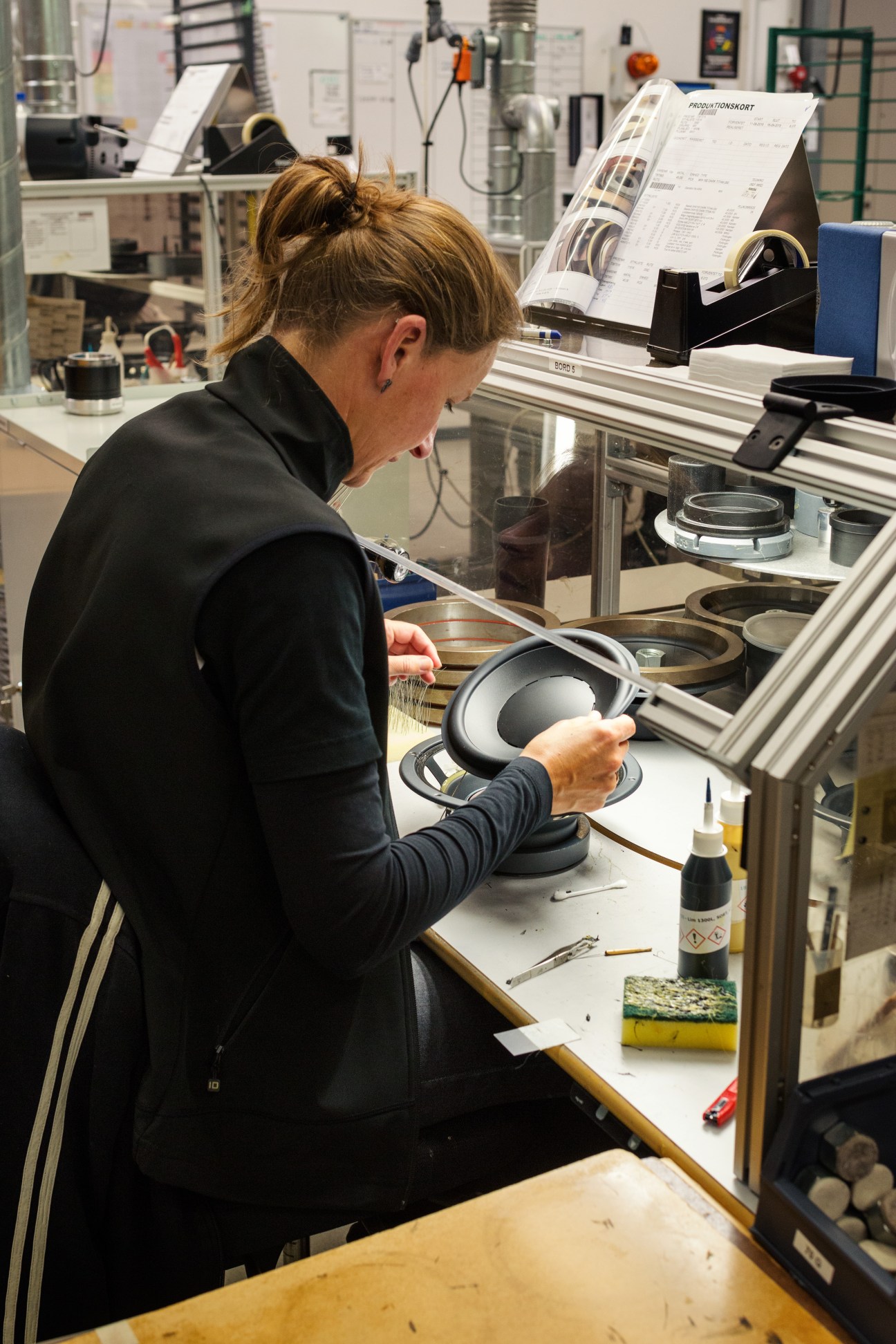 Technician assembles a speaker component at a workbench in the Dynaudio factory.