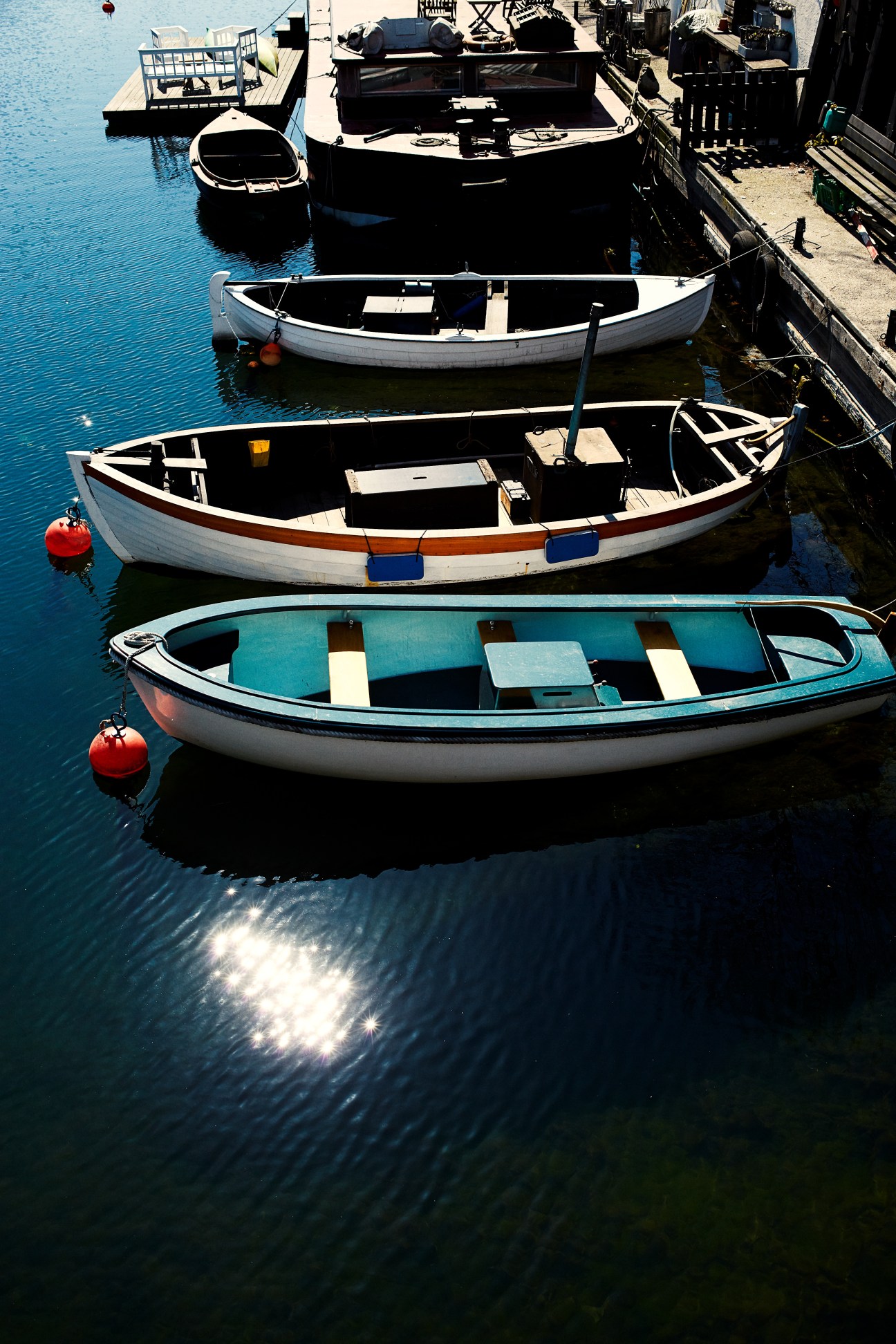 Colorful fishing boats moored in clear blue water at a harbor dock.
