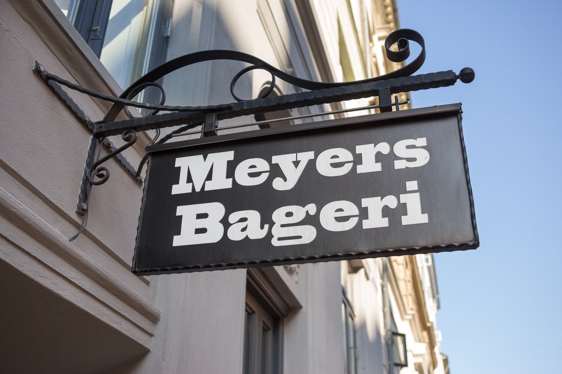 Meyers Bageri storefront sign with ornate black bracket against white building facade.