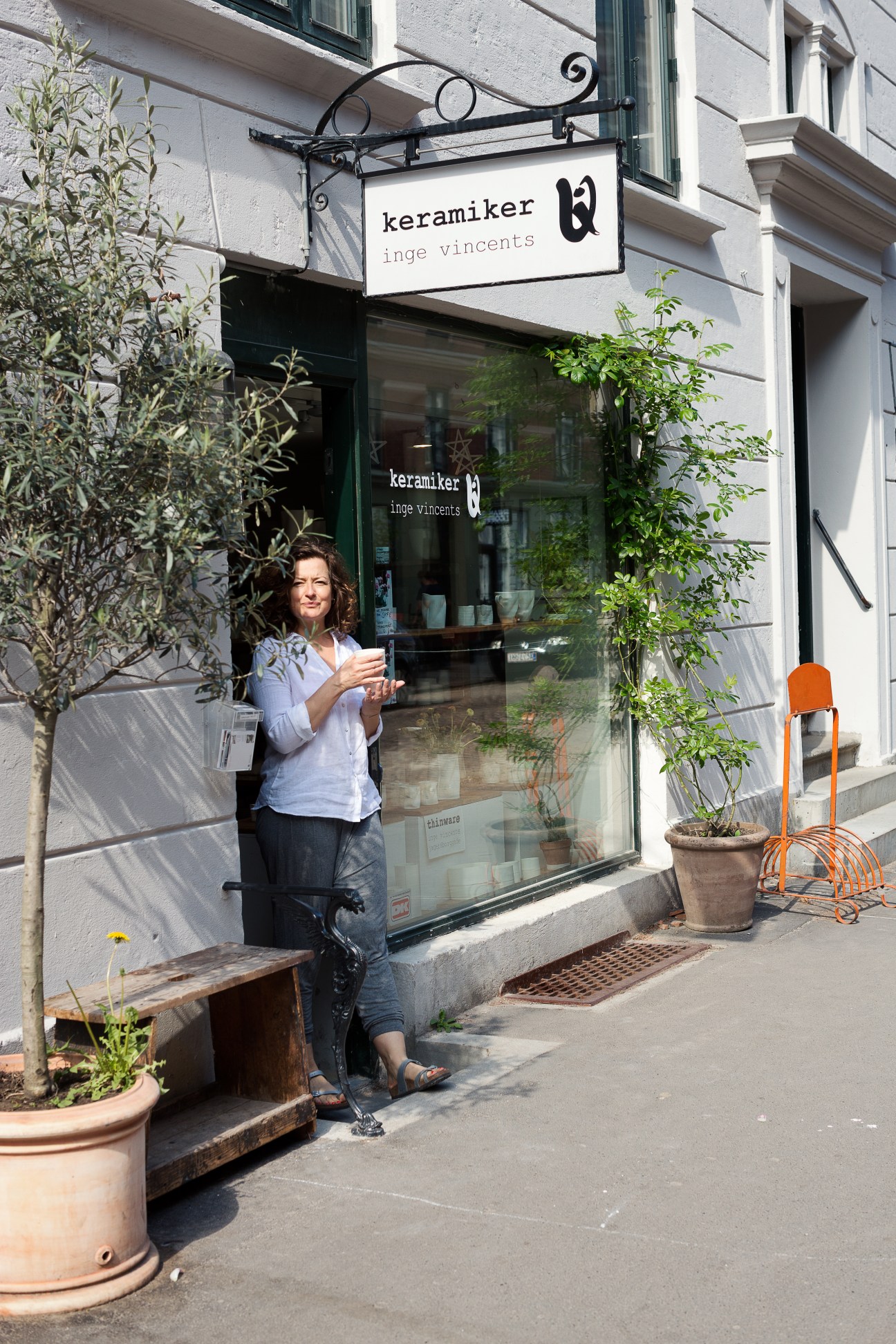Ceramicist Inge Vincents stands outside her shop on Jaegersborggade displaying a ceramic piece.
