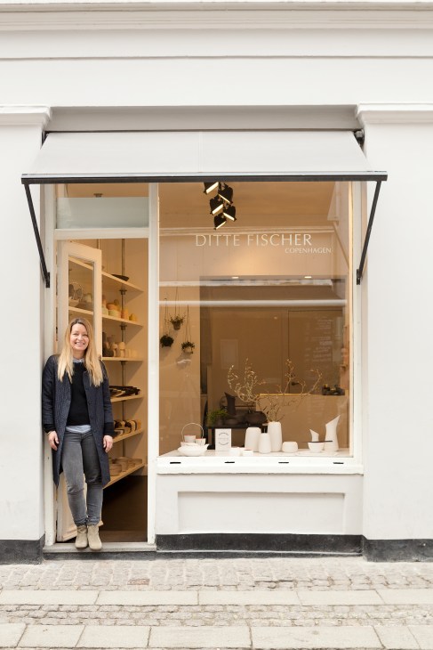 Ditte Fischer stands outside her minimalist porcelain shop on a Copenhagen street.