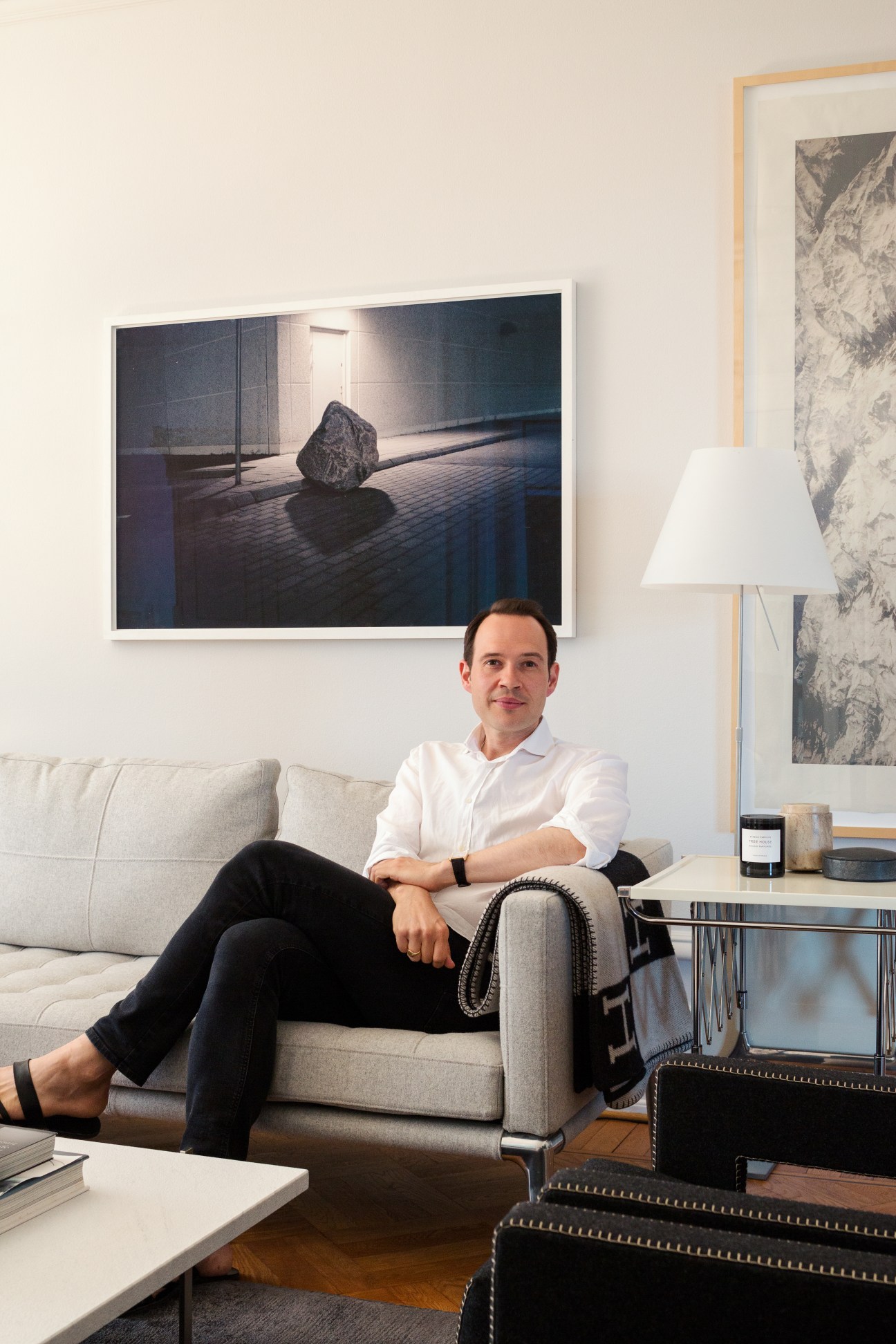 Architect Henrik Kjaer Christiansen sits on a beige sofa in his minimalist apartment.